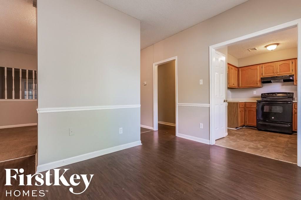 a living room and kitchen with wood floors and white walls