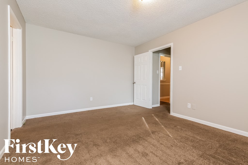 a living room with a carpeted floor and a door to a bathroom