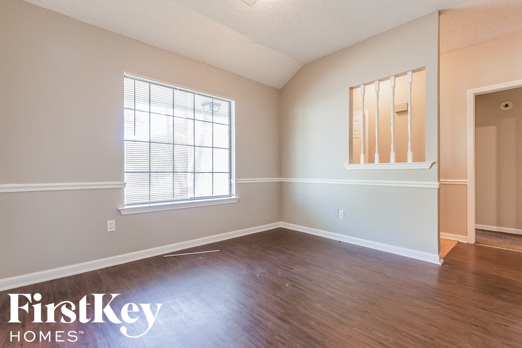 an empty living room with wood floors and a window