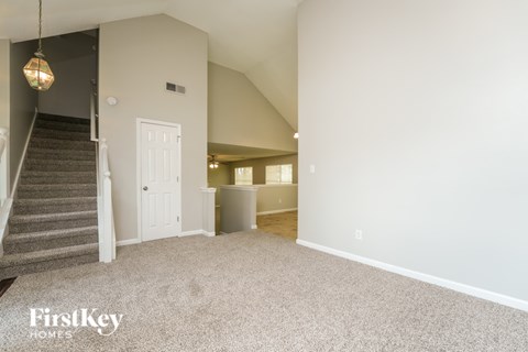 A spacious room with a staircase and a door in the background.