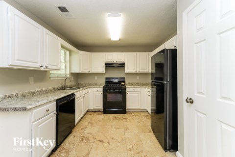 A kitchen with black appliances and white cabinets.