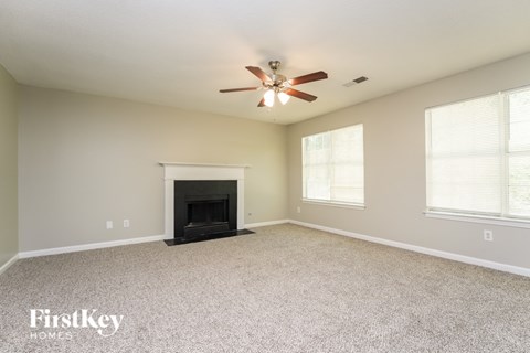 A spacious living room with a fireplace and a ceiling fan.
