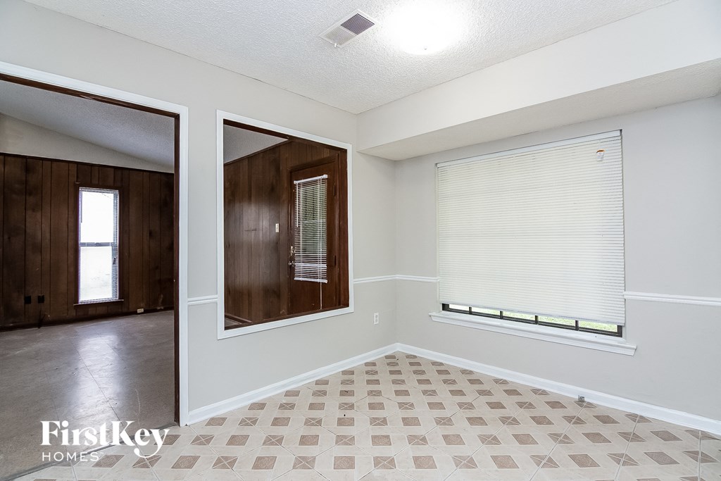 an empty living room with a window and a door to a hallway