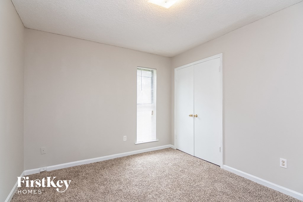 a bedroom with carpet and a door to a closet