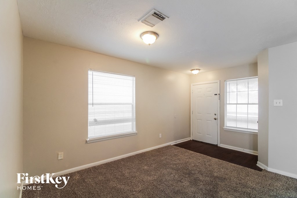 the spacious living room with carpet and a door to the bedroom