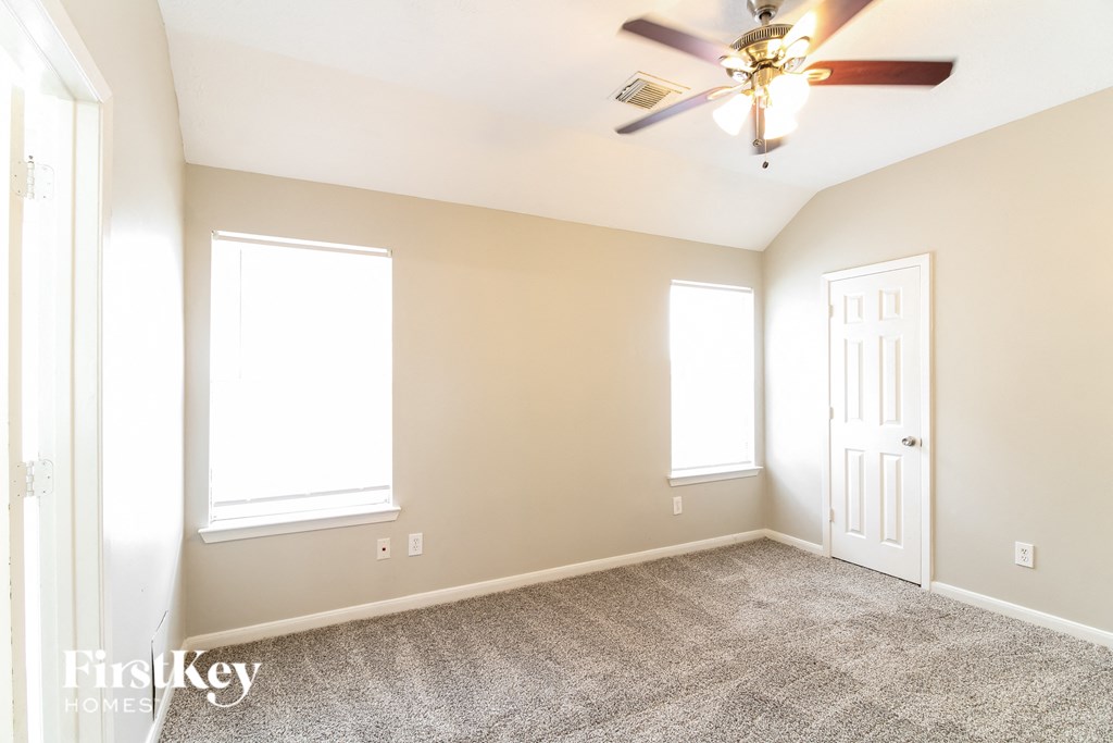 a empty room with a ceiling fan and two windows