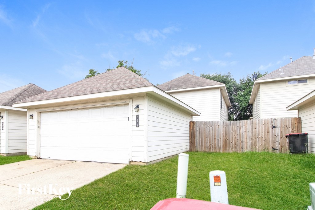 a backyard with a white garage and a wooden fence