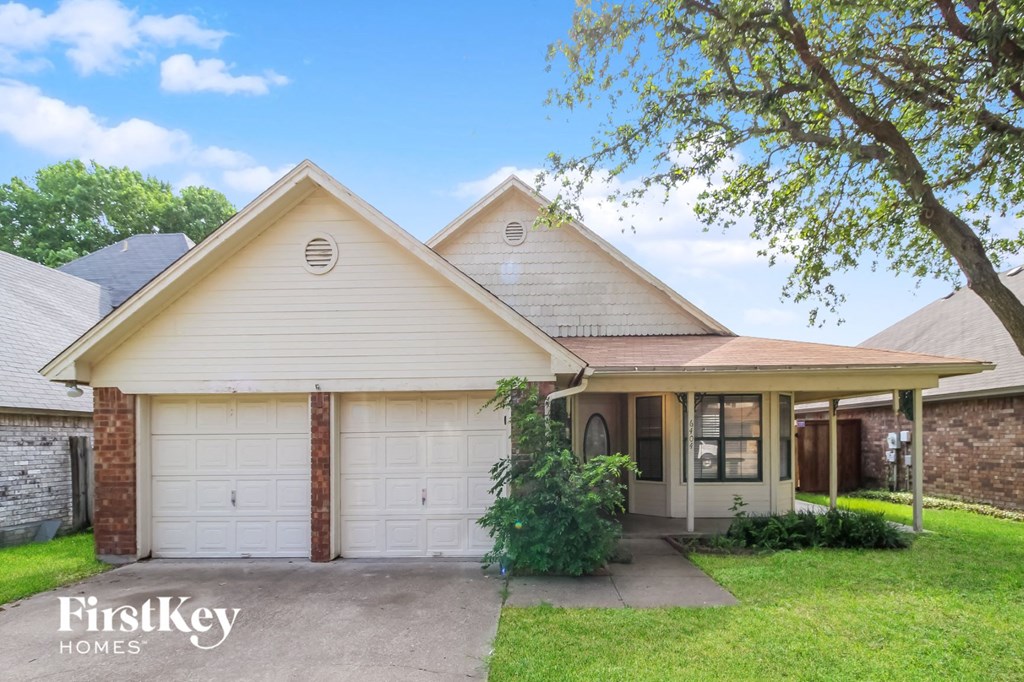 a home with white garage doors and a tree