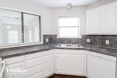 a kitchen with white cabinets and a sink and a window