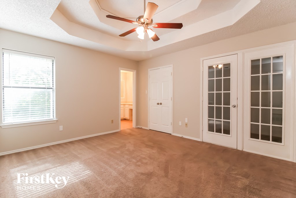 an empty living room with a ceiling fan and a door to a closet
