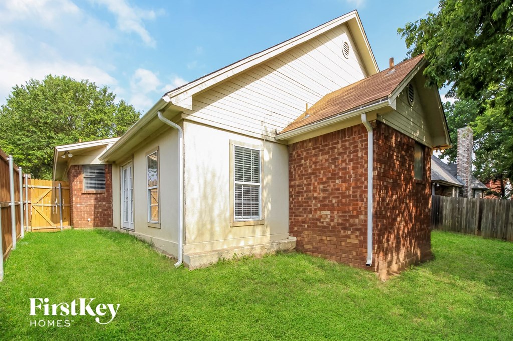 a small brick house with a yard and a fence