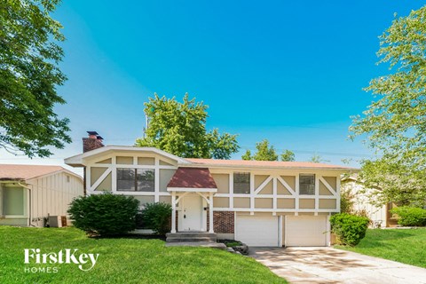 A house with a garage and a tree in front of it.