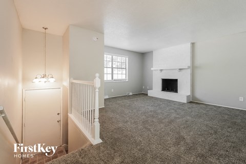 A spacious living room with a fireplace and a carpeted floor.