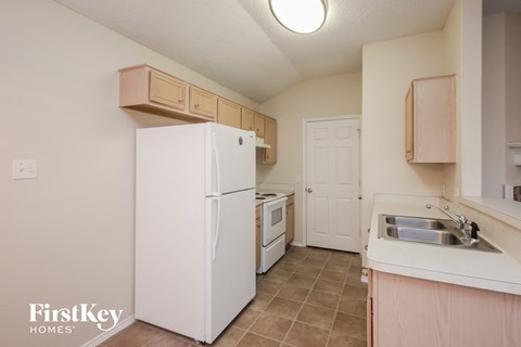 A kitchen with a white fridge and a sink.