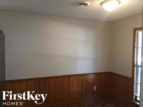 a dining room with wood paneling and a white wall