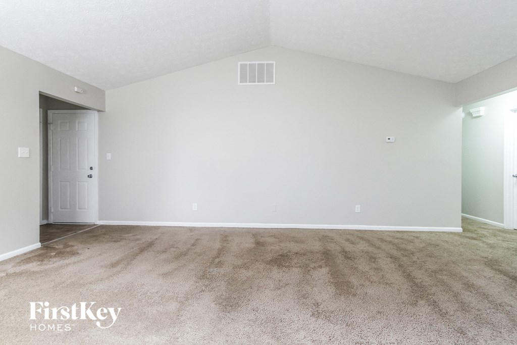 the spacious living room with carpeting and white walls