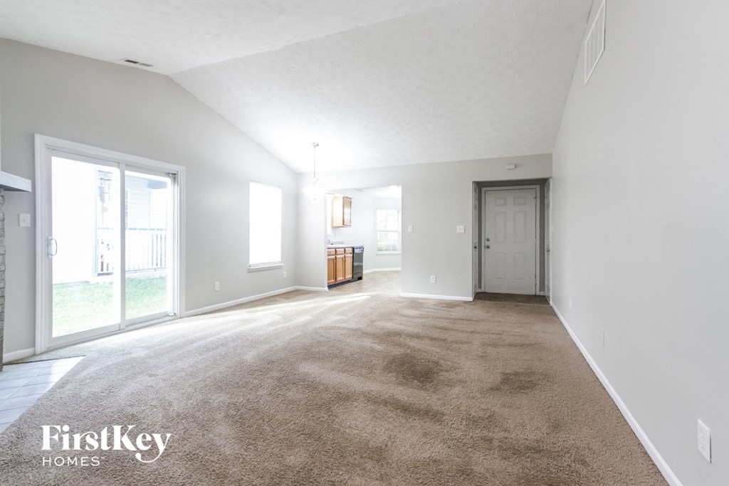 a living room with carpet and a door to a kitchen