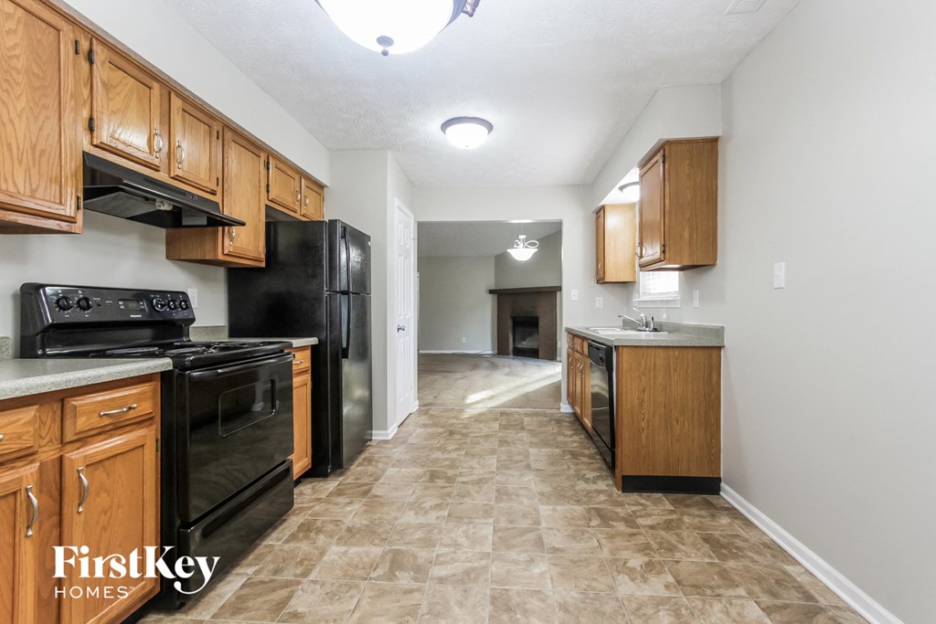 an empty kitchen with black appliances and wooden cabinets