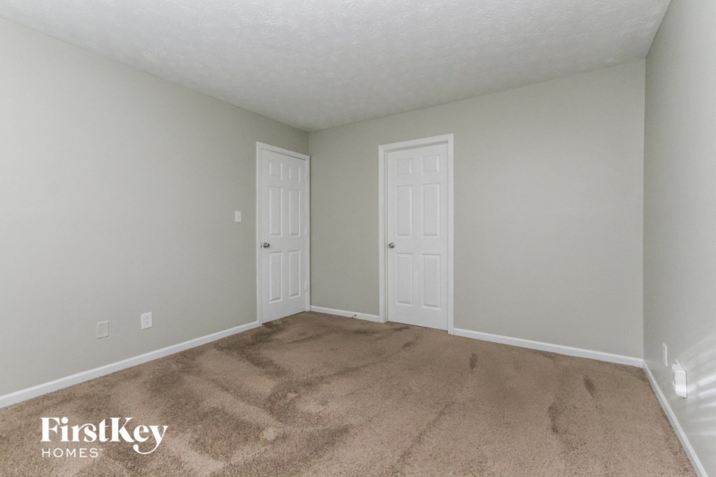 a bedroom with a carpeted floor and two doors