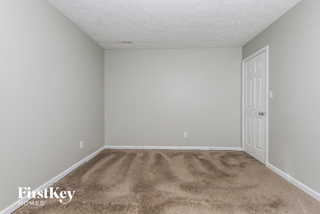 a bedroom with a carpeted floor and a white door