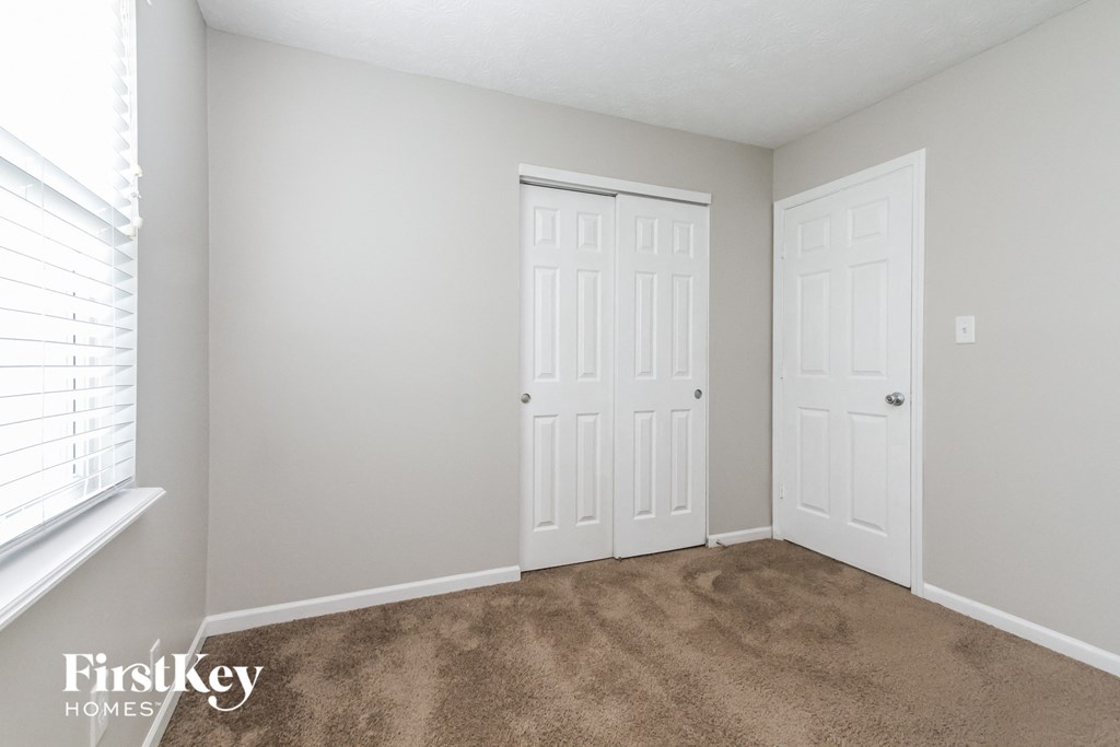a bedroom with two doors and a carpeted floor and a window