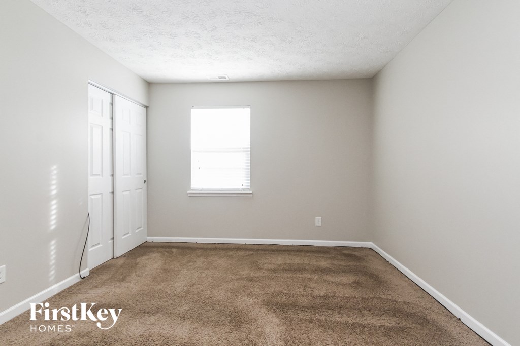a carpeted room with a window and a closet