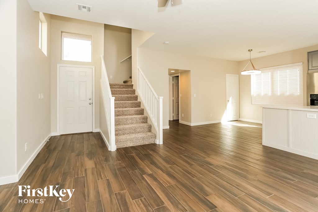 the living room and entryway of an open floor plan with hardwood flooring