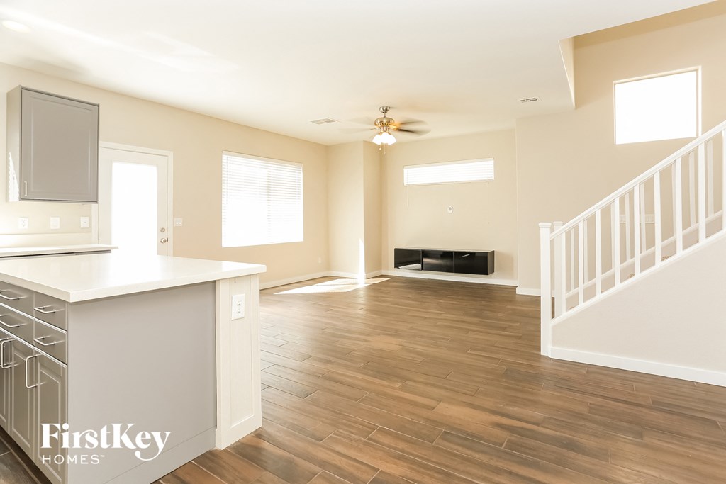a kitchen and living room with hardwood floors and a ceiling fan