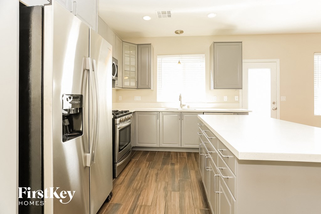 a white kitchen with stainless steel appliances and white counter tops