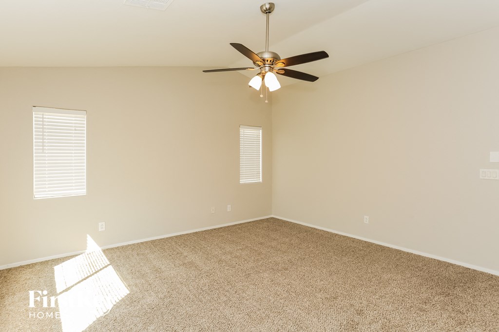 an empty living room with a ceiling fan and a carpet