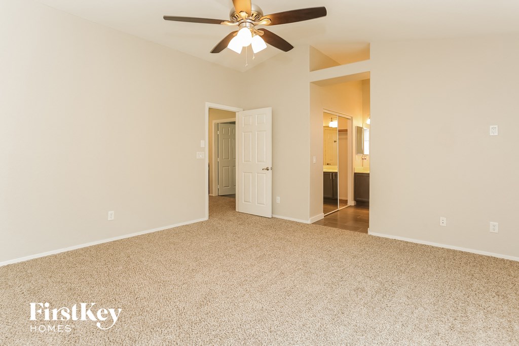 the spacious living room with ceiling fan and carpeting