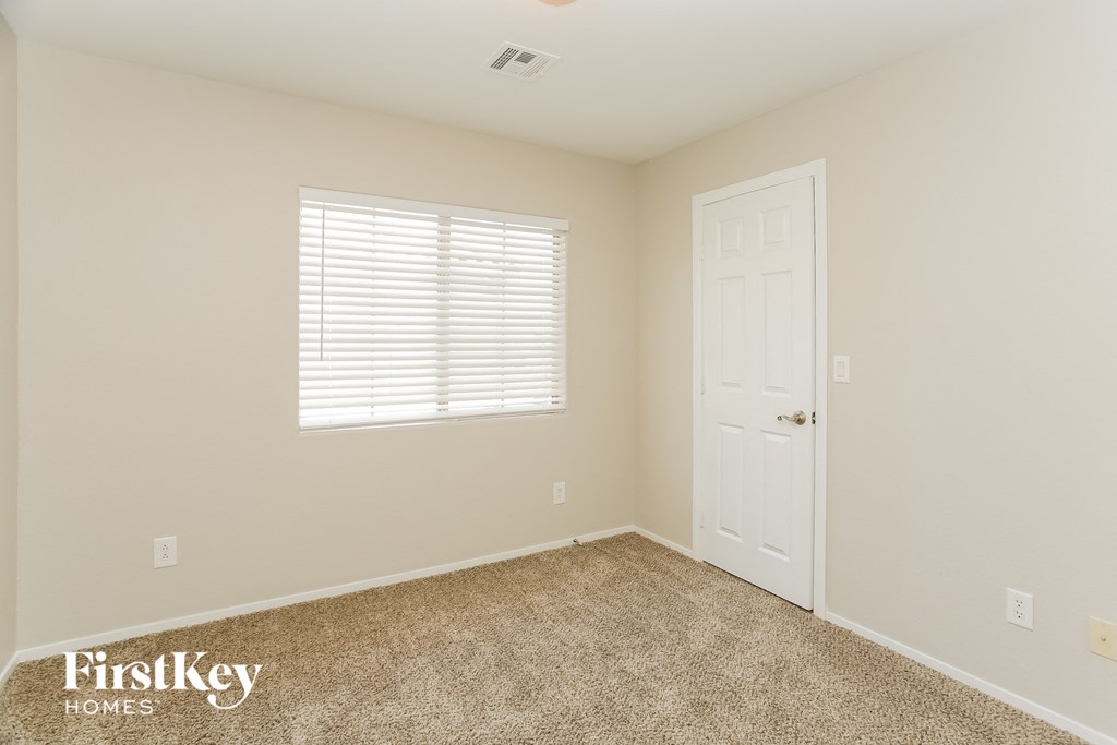 a bedroom with a door and a window and a carpeted floor