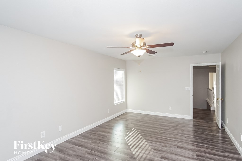 a living room with white walls and a ceiling fan