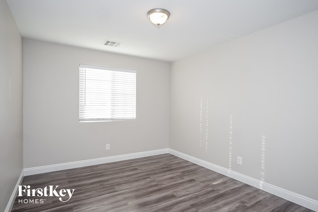 the spacious living room with wood flooring and a window