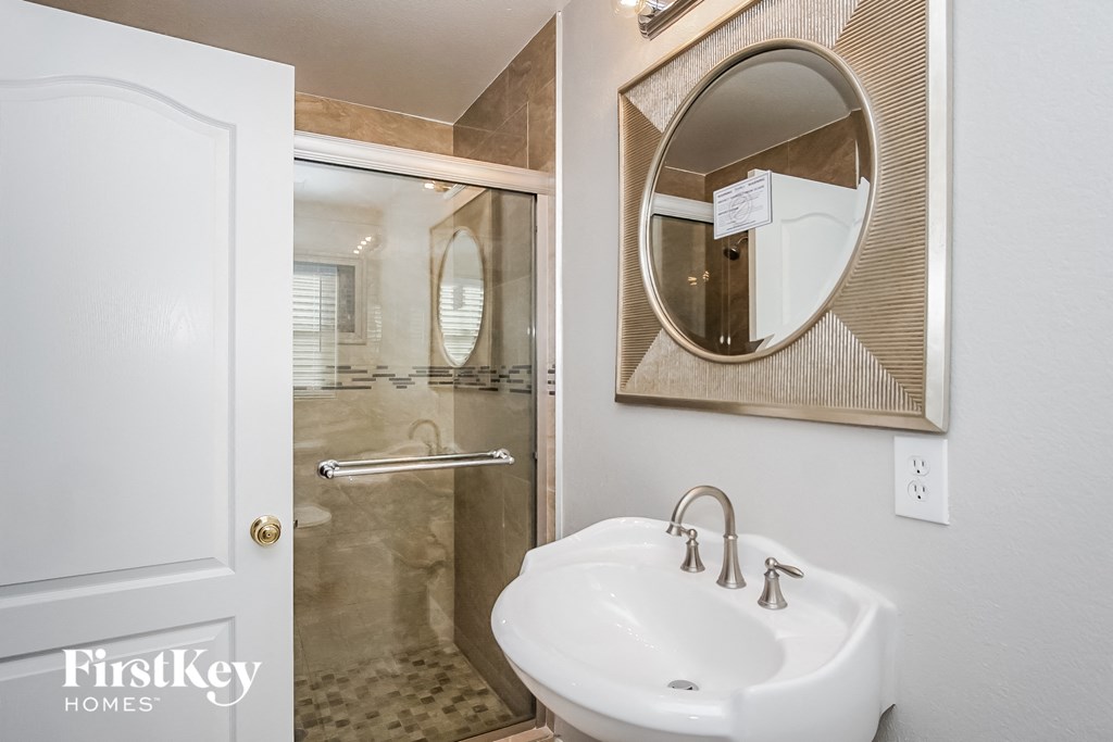 a bathroom with a white sink and a shower and a mirror