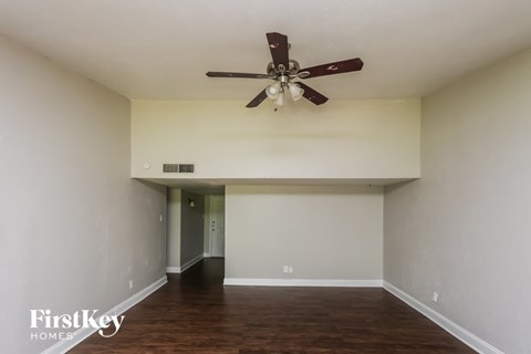 A spacious room with a ceiling fan and wooden flooring.
