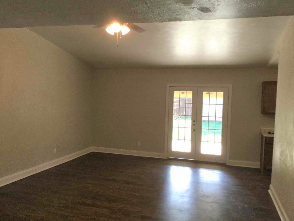 A room with a ceiling fan and a sliding glass door.