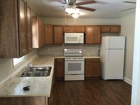 A kitchen with a white fridge, microwave, and oven.