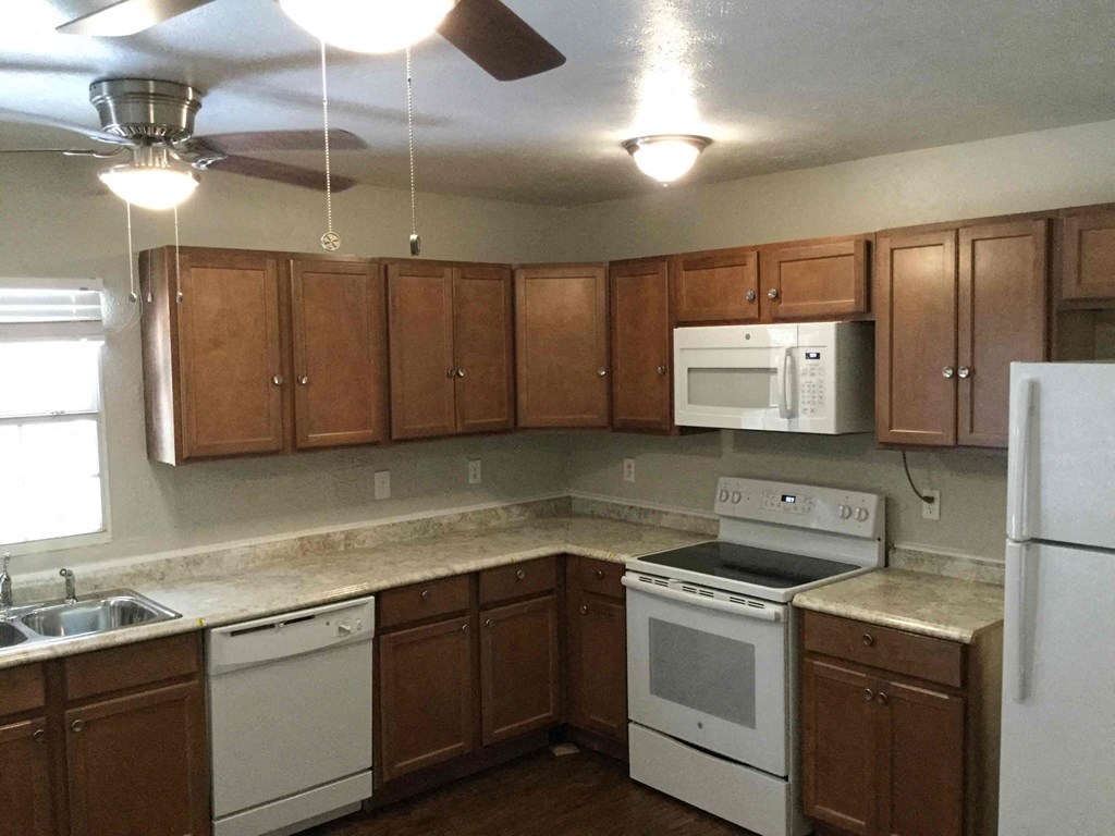 A kitchen with white appliances and brown cabinets.