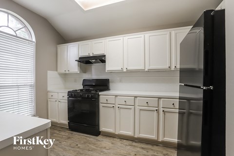 a kitchen with white cabinets and a black stove and refrigerator