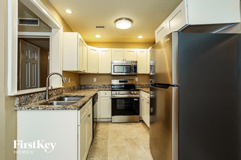 A kitchen with a stainless steel refrigerator and white cabinets.