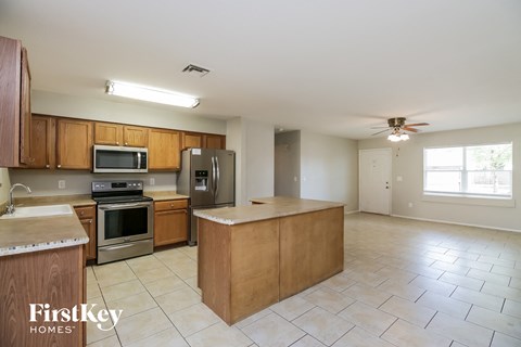 A kitchen with wooden cabinets and a tiled floor.