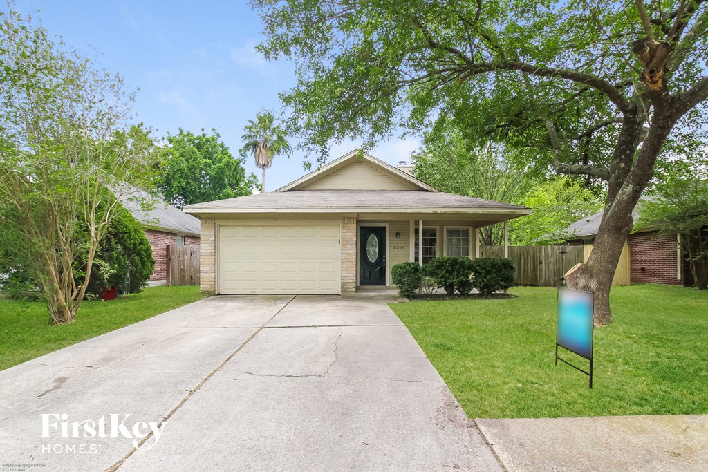 a small house with a driveway and a blue sign in front of it