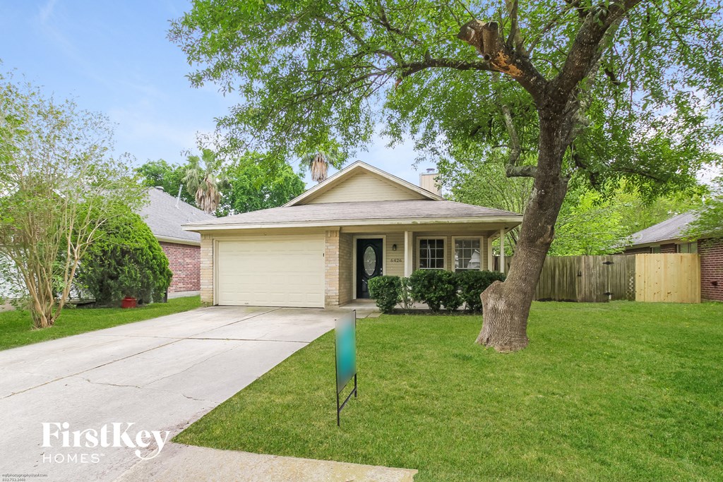 a small white house with a yard and a tree