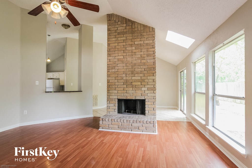 the living room has a brick fireplace and hardwood floors