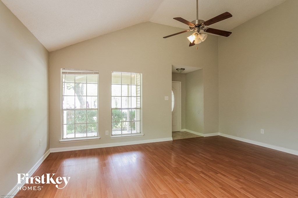 an empty living room with wood floors and a ceiling fan