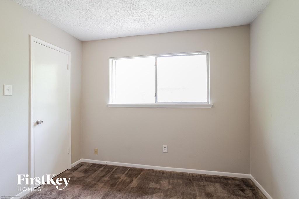 a bedroom with a window and a carpeted floor