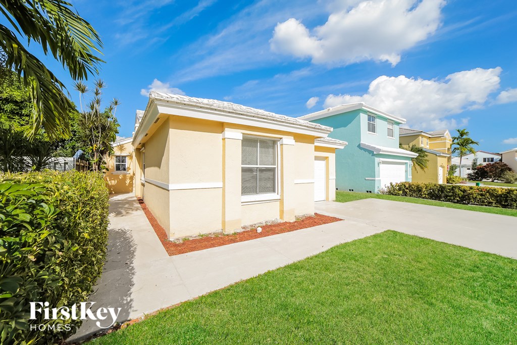 a small yellow and blue house with a driveway and lawn