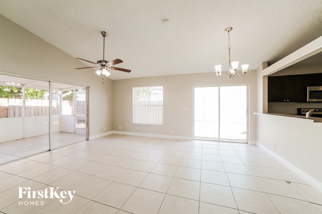 an empty living room with a ceiling fan and a tv