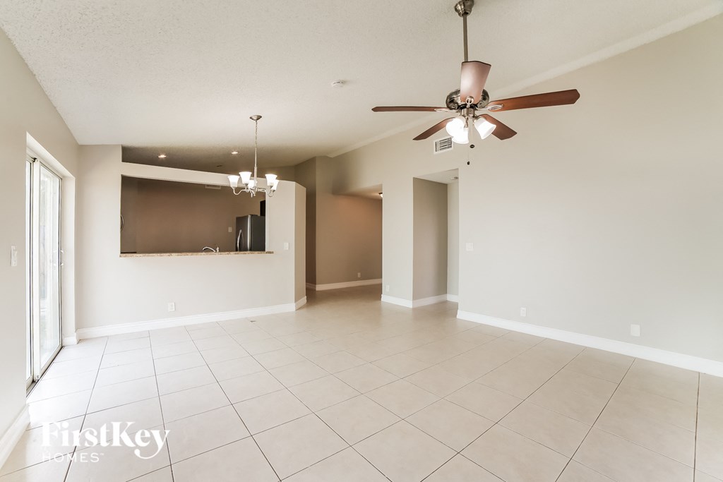 an empty living room with a ceiling fan and tiled floors